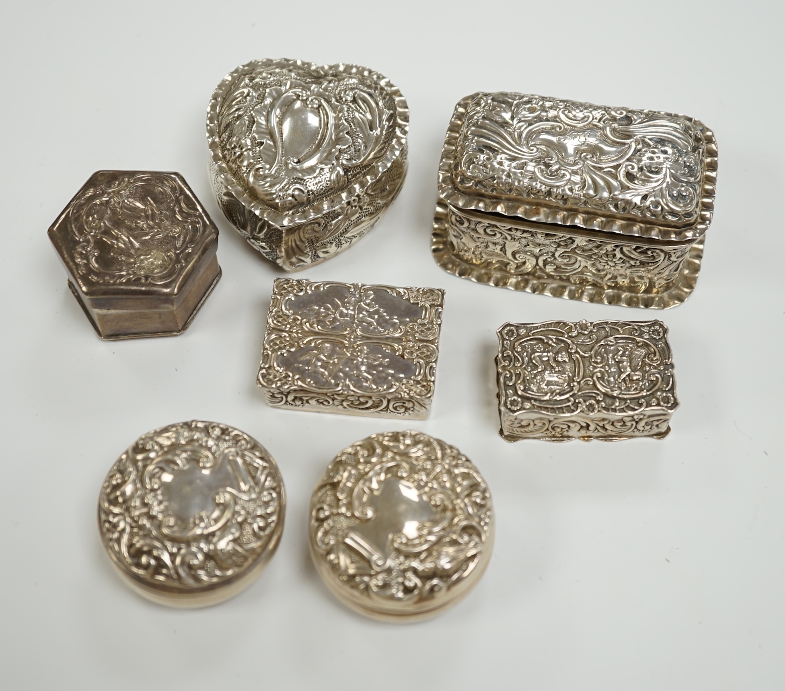 Six assorted early 20th century and later repousse silver boxes, largest 75mm and one similar white metal box.